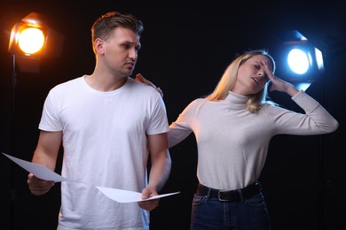 Casting call. Emotional woman and man with script performing on black background