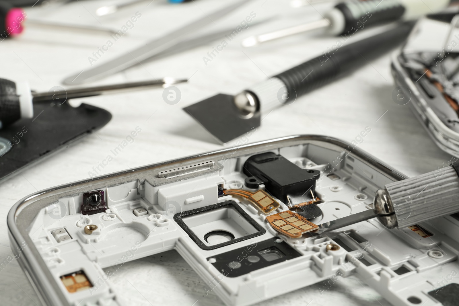 Photo of Damaged smartphone and repair tool on table, closeup