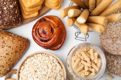 Photo of Different gluten free products on white tiled table, flat lay