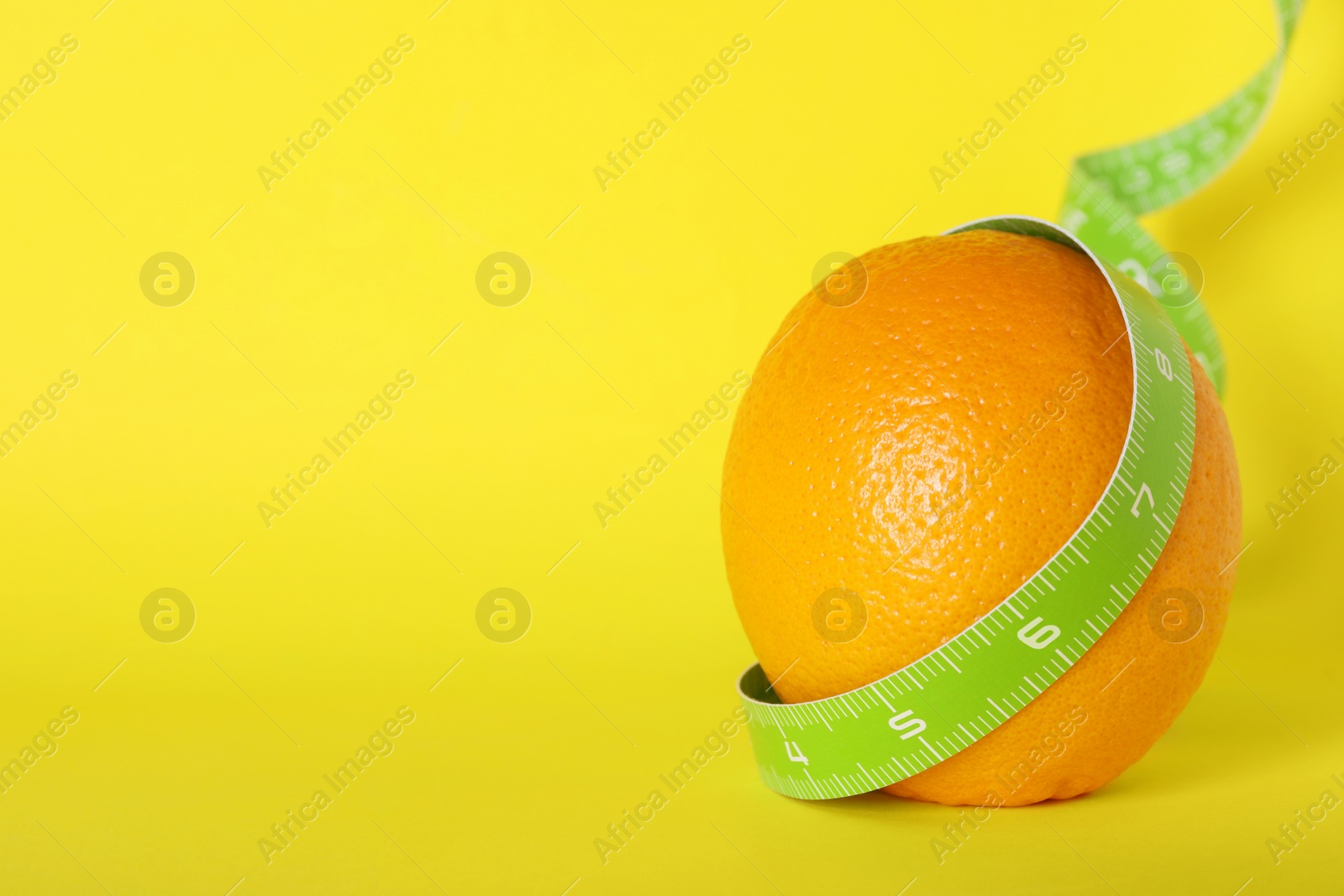 Photo of Cellulite problem. Orange with measuring tape on yellow background, space for text