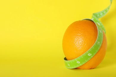 Photo of Cellulite problem. Orange with measuring tape on yellow background, space for text