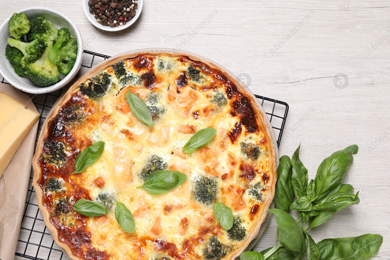 Photo of Delicious homemade salmon quiche and ingredients on wooden table, flat lay