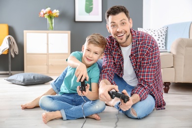 Little boy and his dad playing video game together at home