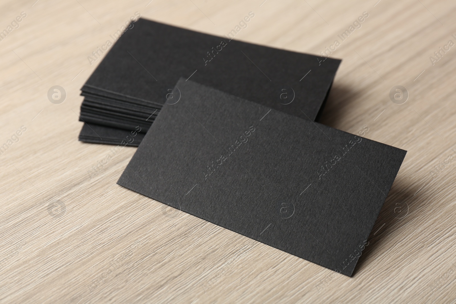 Photo of Blank black business cards on wooden table, closeup. Mockup for design