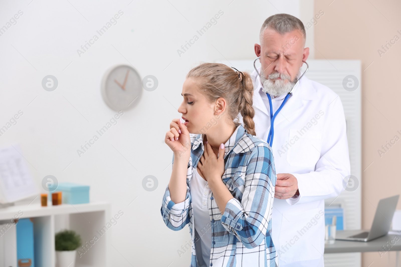 Photo of Doctor examining coughing young woman at clinic