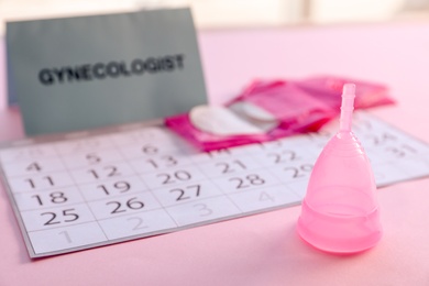 Photo of Menstrual cup and calendar on table. Gynecological care