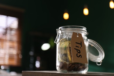 Photo of Glass jar with tips on wooden table indoors, closeup. Space for text