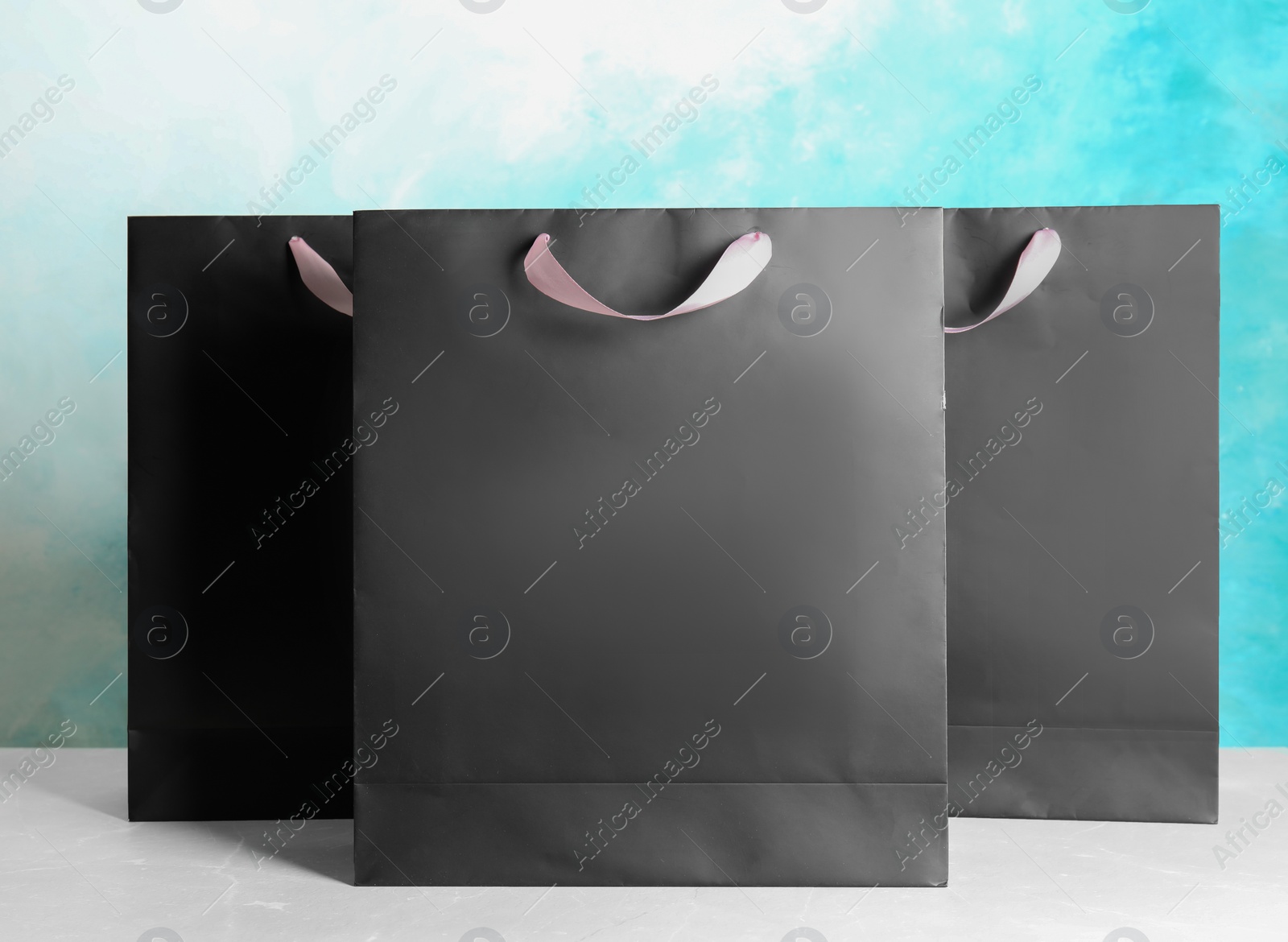 Photo of Paper shopping bags on table against color background. Mock up for design