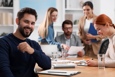 Photo of Team of employees working together in office. Happy man at table indoors