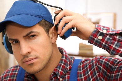 Photo of Worker wearing safety headphones indoors. Hearing protection device