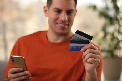 Photo of Man using smartphone and credit card for online payment at home