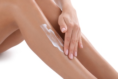 Photo of Young woman with perfect skin applying cream on white background, closeup of legs. Beauty and body care