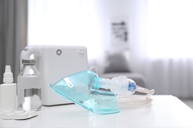 Modern nebulizer with face mask and medicines on white table indoors. Inhalation equipment