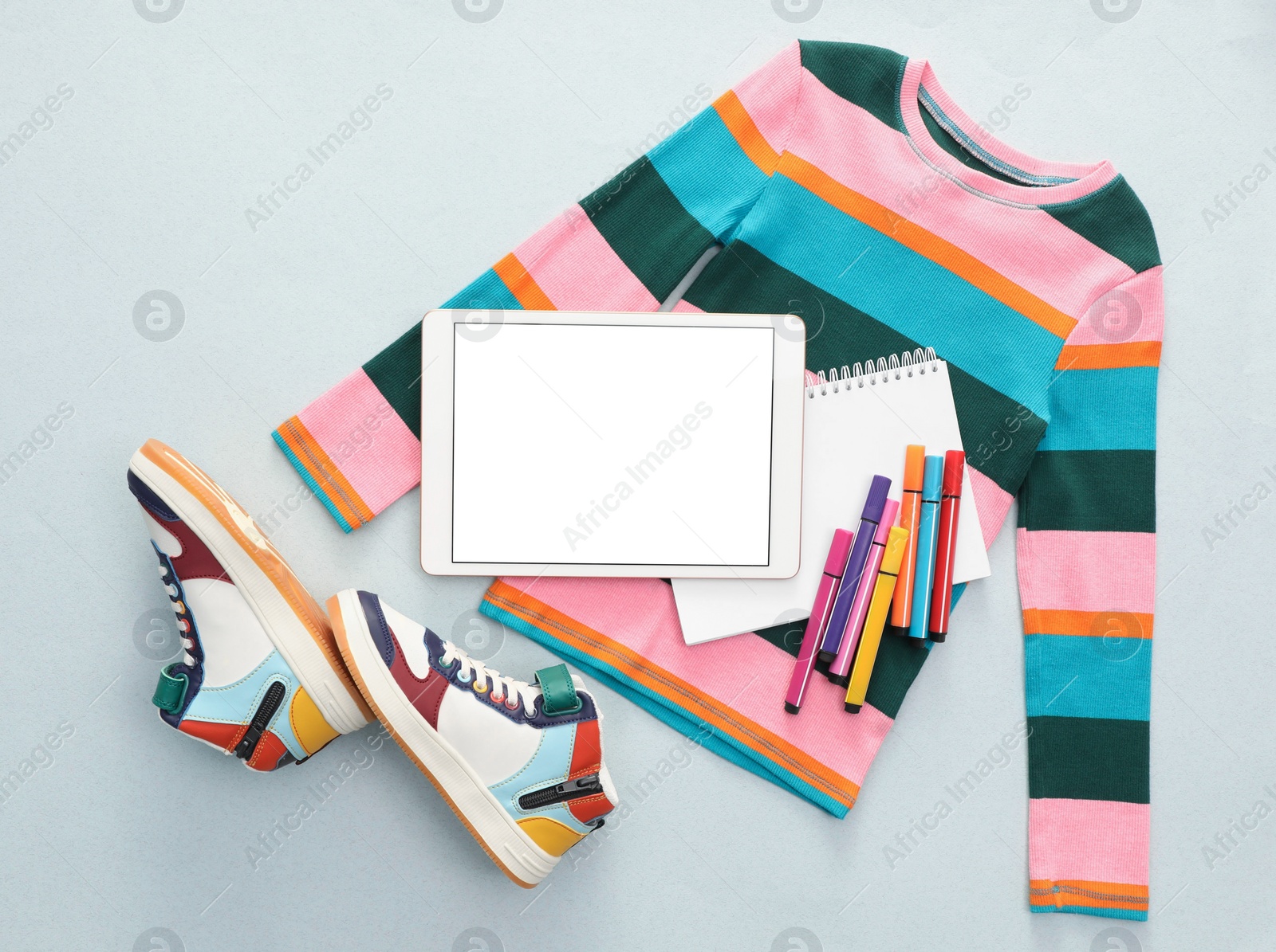 Photo of Modern tablet, clothes and stationery on light background, flat lay. Space for text