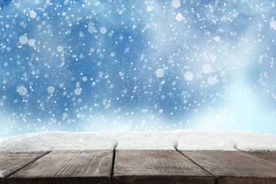 Image of Wooden surface with snow against blue background, bokeh effect