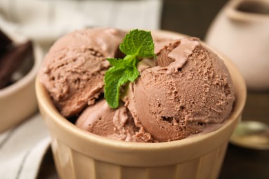 Tasty chocolate ice cream and mint in bowl, closeup