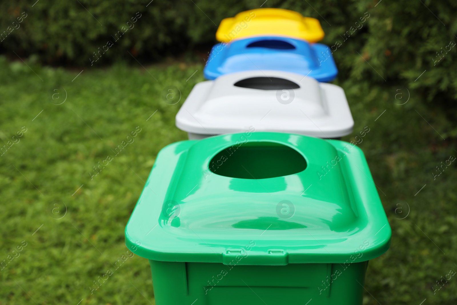 Photo of Many color recycling bins on green grass outdoors, space for text