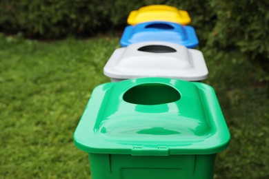 Many color recycling bins on green grass outdoors, space for text