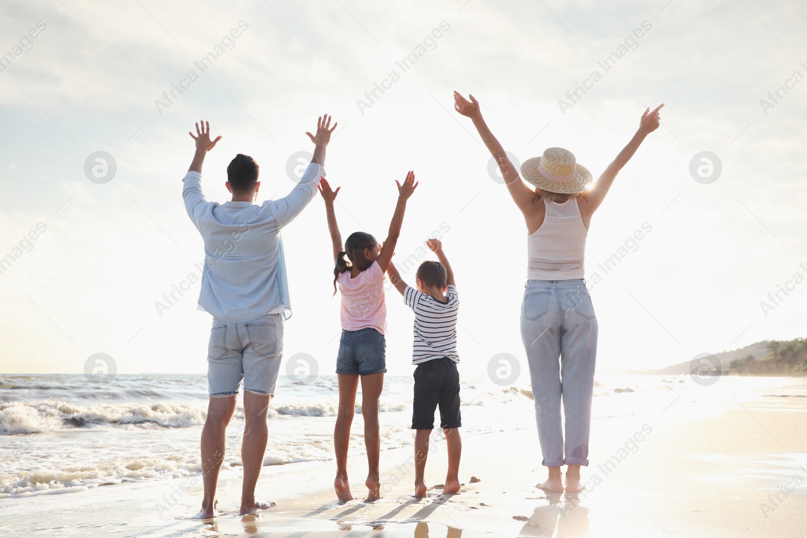 Photo of Family on sandy beach near sea, back view. Summer vacation