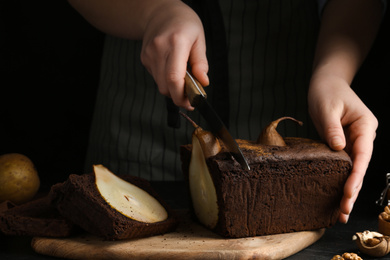 Photo of Woman cutting tasty pear bread at table, closeup. Homemade cake