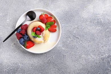 Photo of Delicious vanilla fondant served with fresh berries on grey textured table, top view. Space for text