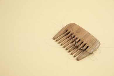 Wooden comb with lost hair on beige background. Space for text