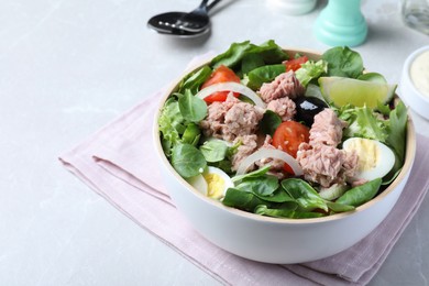 Photo of Bowl of delicious salad with canned tuna and vegetables on light table, space for text