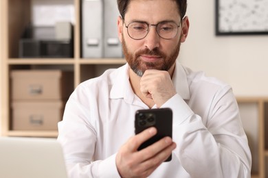 Photo of Handsome man using smartphone in office, selective focus