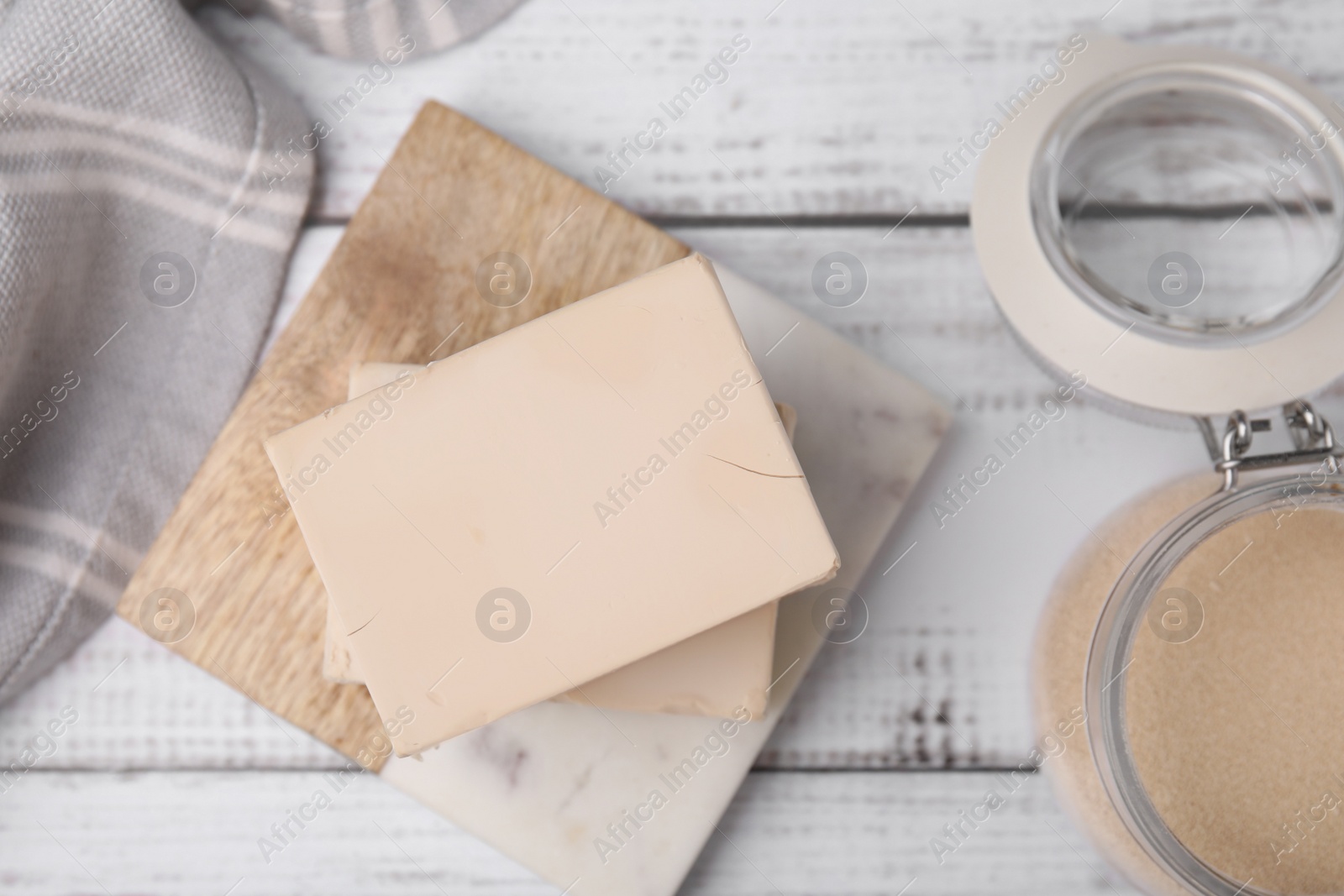 Photo of Blocks of compressed yeast on white wooden table, flat lay