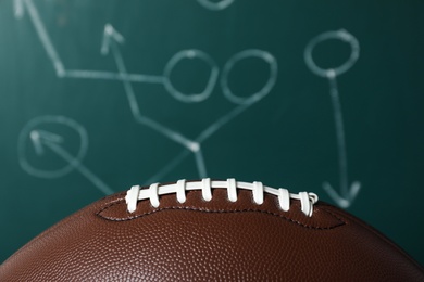 Photo of Leather American football on chalkboard with scheme of game, closeup