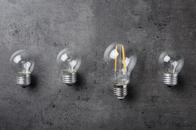 Vintage and modern lamp bulbs on grey stone surface, top view