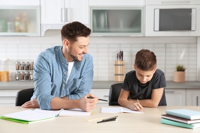 Dad helping his son with homework in kitchen