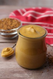 Tasty mustard sauce in jar on wooden table, closeup