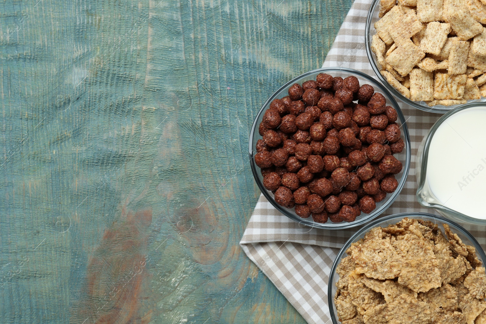 Photo of Different delicious breakfast cereals on blue wooden table, flat lay. Space for text