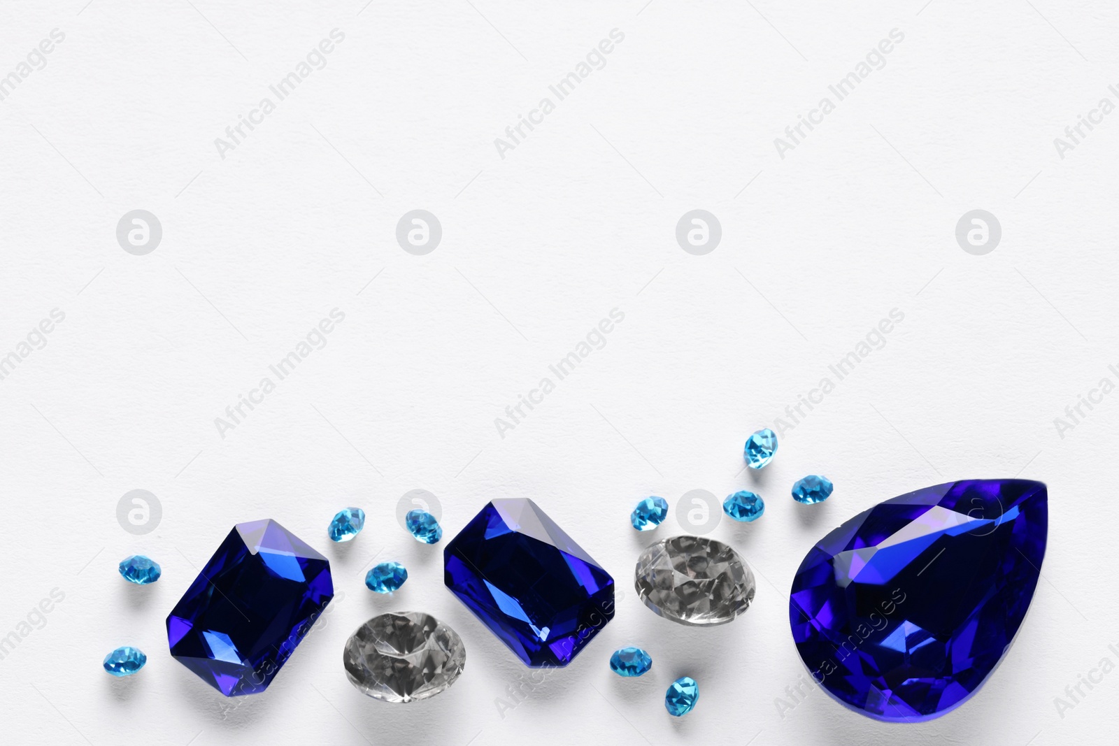 Photo of Different beautiful gemstones for jewelry on white background, top view. Space for text