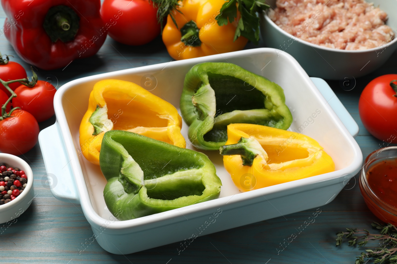 Photo of Making stuffed peppers. Vegetables and ground meat on light blue wooden table