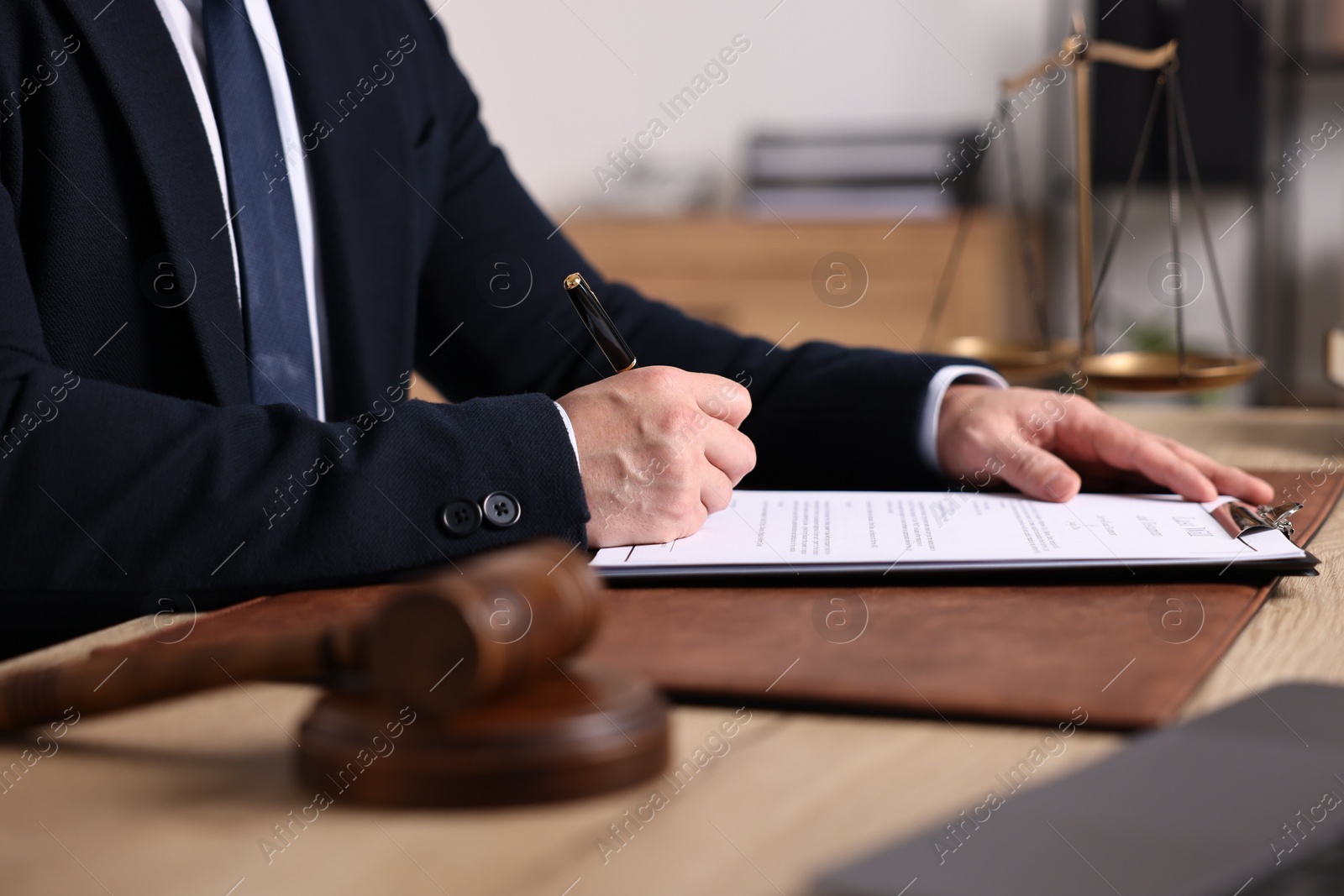 Photo of Notary writing notes at wooden table in office, closeup