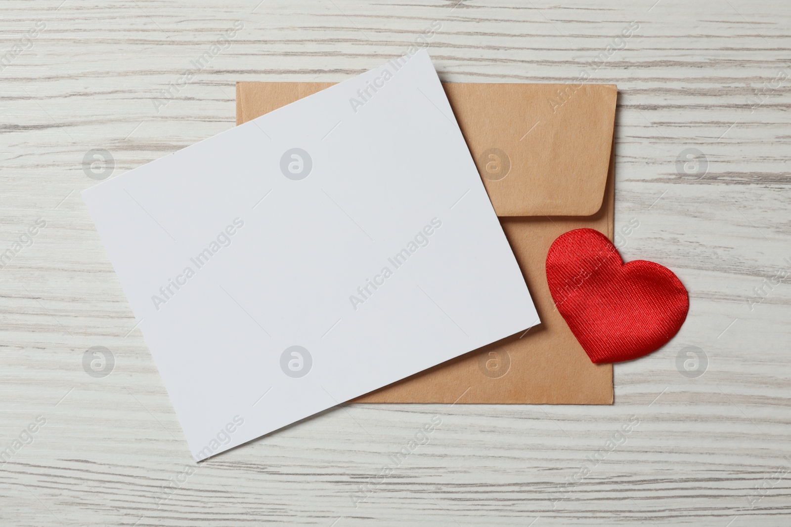 Photo of Blank card, envelope and decorative heart on white wooden background, flat lay with space for text. Valentine's Day celebration