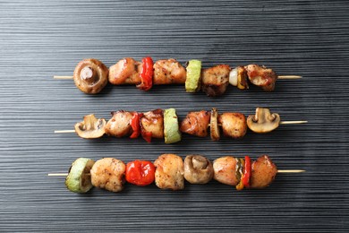 Delicious shish kebabs with vegetables on black table, top view