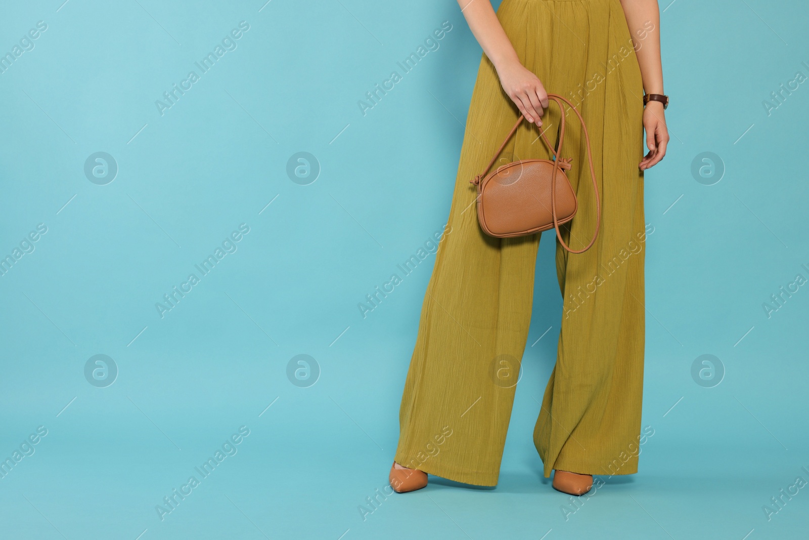 Photo of Woman with stylish bag on light blue background, closeup. Space for text