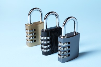 Steel combination padlocks on light blue background, closeup