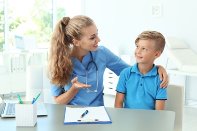 Female medical assistant consulting child in clinic