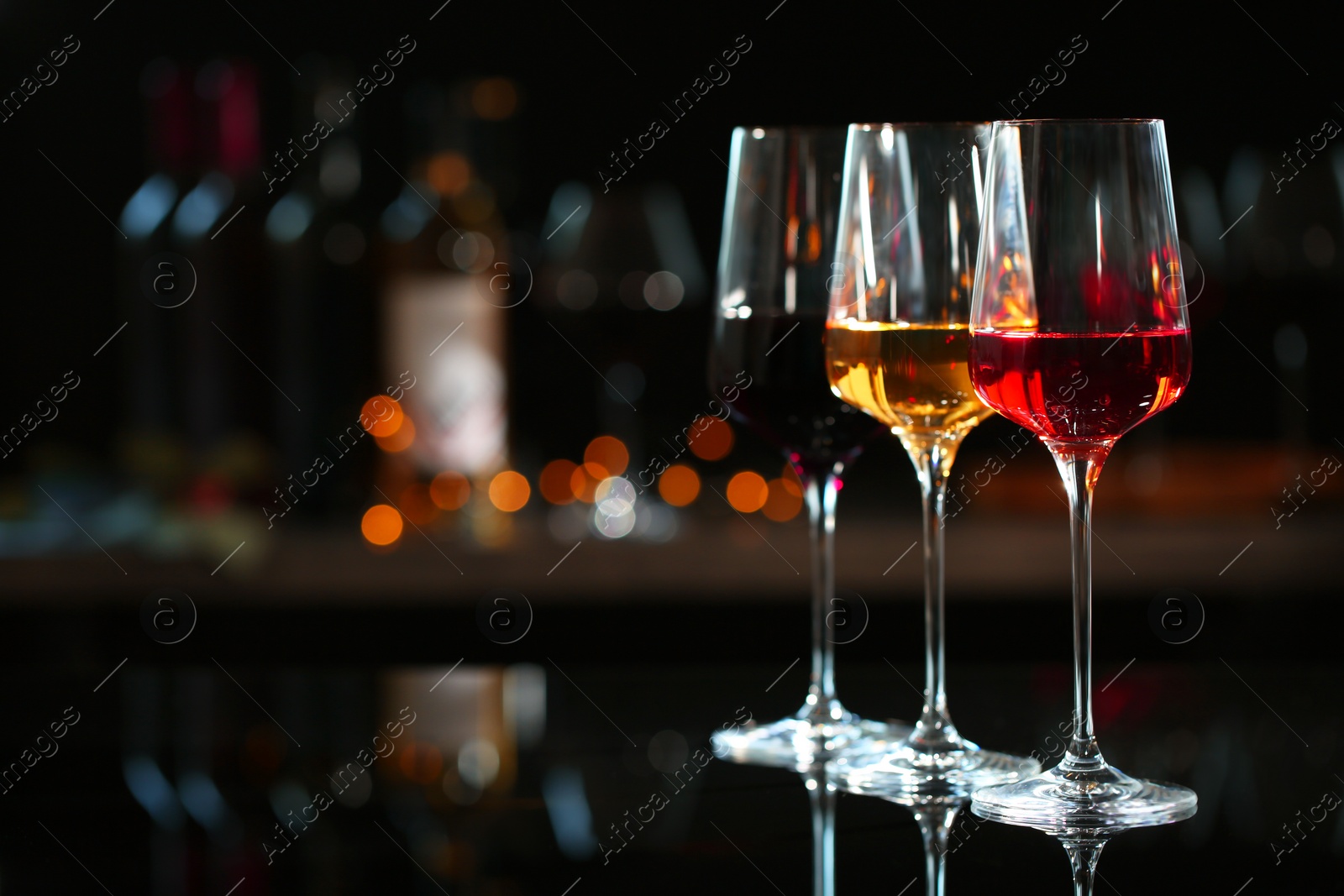 Photo of Row of glasses with different wines on bar counter against blurred background. Space for text