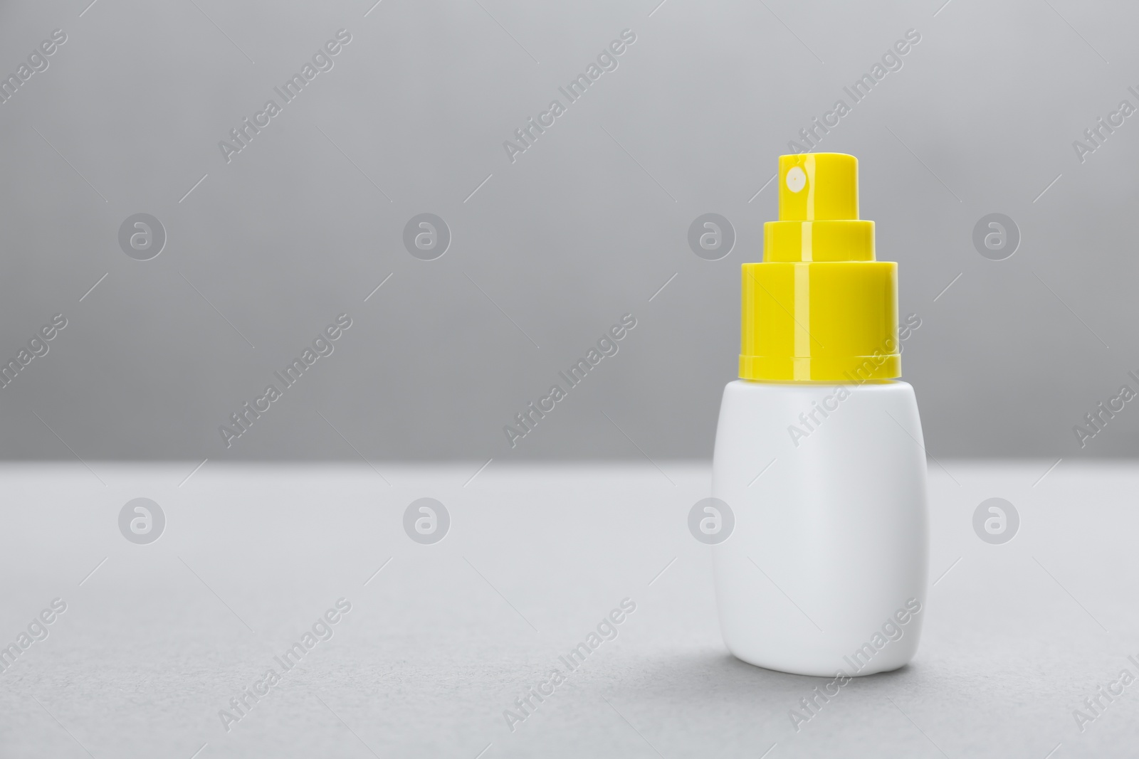 Photo of Bottle with insect repellent spray on grey background, space for text