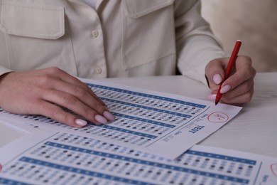 School grade. Teacher writing letter A with plus symbol on answer sheet at white table, closeup