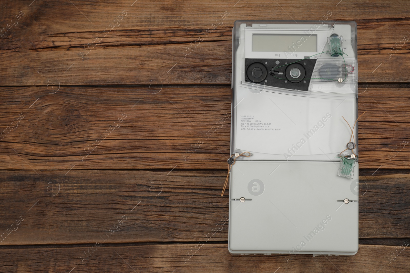 Photo of Electric meter on wooden background, top view with space for text. Measuring device