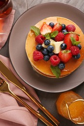 Photo of Delicious pancakes with fresh berries, honey and butter served on grey table, flat lay
