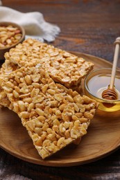 Photo of Delicious peanut bars (kozinaki) and dipper with honey on wooden table