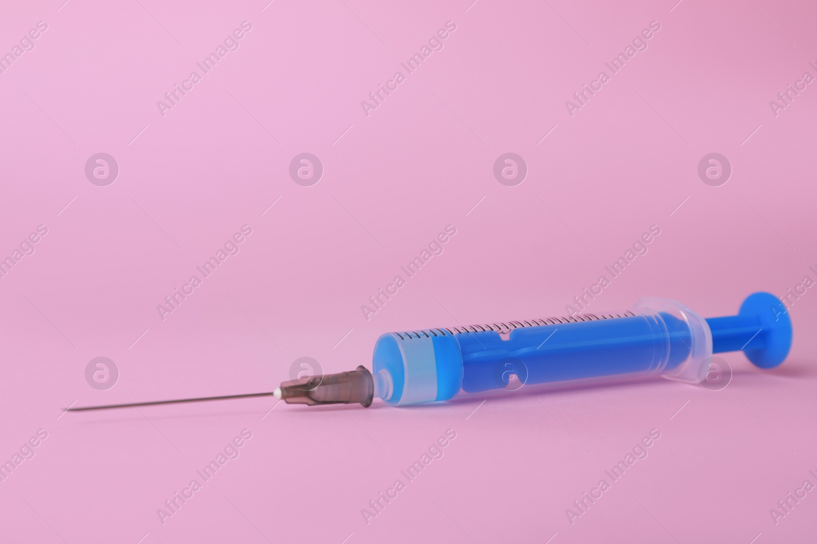 Photo of Disposable syringe with needle and medicine on pink background, space for text