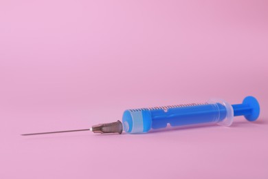Disposable syringe with needle and medicine on pink background, space for text